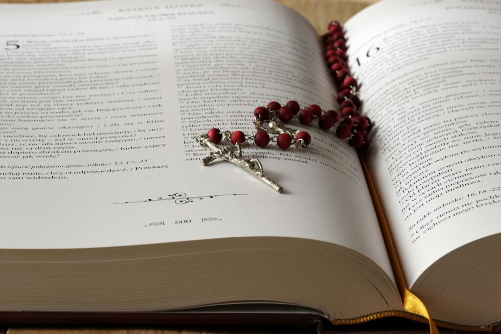 pexels-photo-236339-236339 Open Bible with red rosary beads draped on pages, symbolizing faith and devotion.